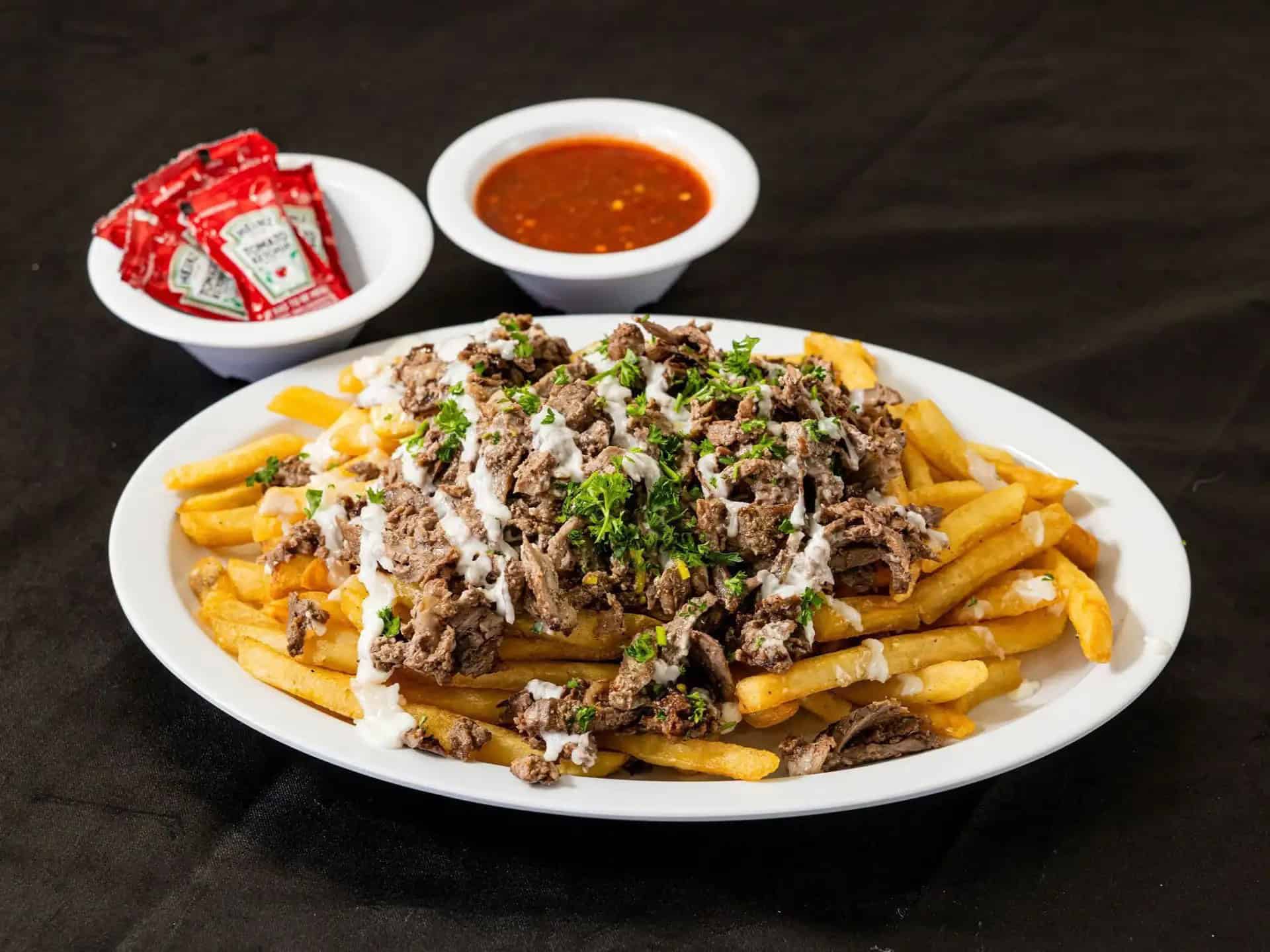 Beef Shawarma Fries at Shawarma House SD — crispy seasoned fries loaded with hand-shaved beef shawarma, salad, and toum or tahini — Iraqi-Mediterranean in Ocean Beach
