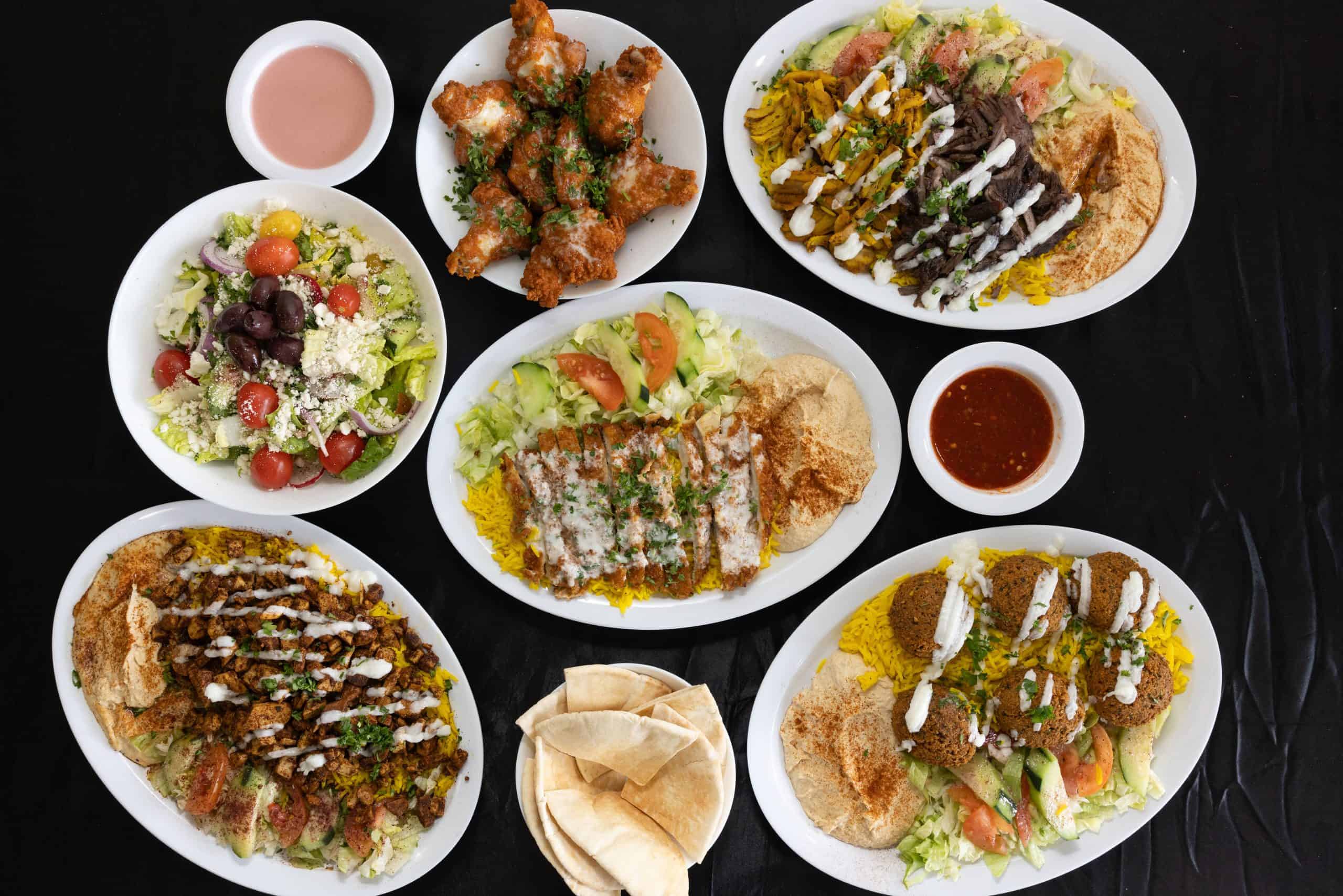 Cover spread at Shawarma House SD — overhead view of plates, salads, hummus, and pita — Iraqi-Mediterranean restaurant in Ocean Beach, San Diego.