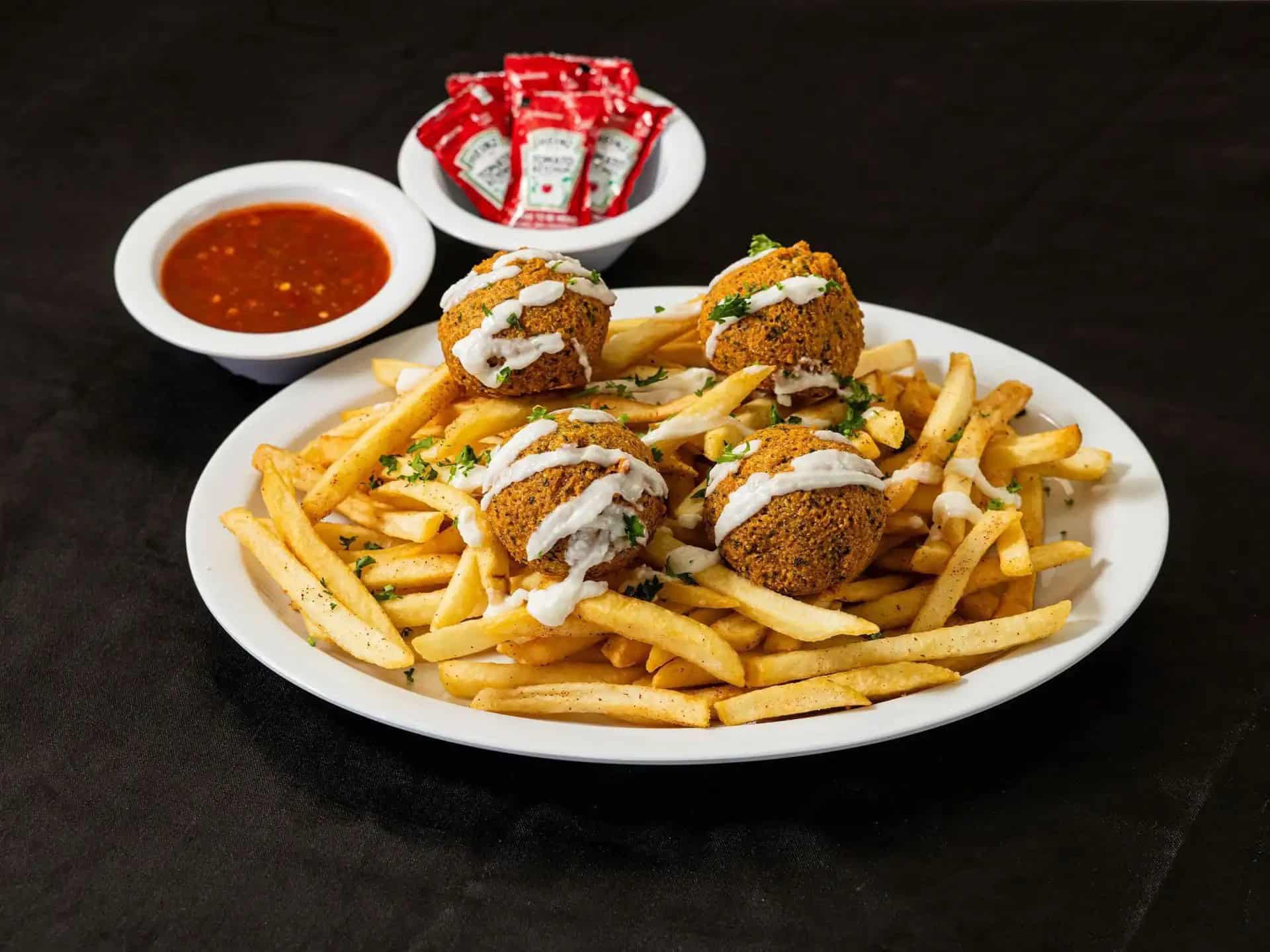 Falafel Fries at Shawarma House SD — crispy seasoned fries loaded with hand-formed chickpea falafel and tahini drizzle — 100% vegan Mediterranean in Ocean Beach