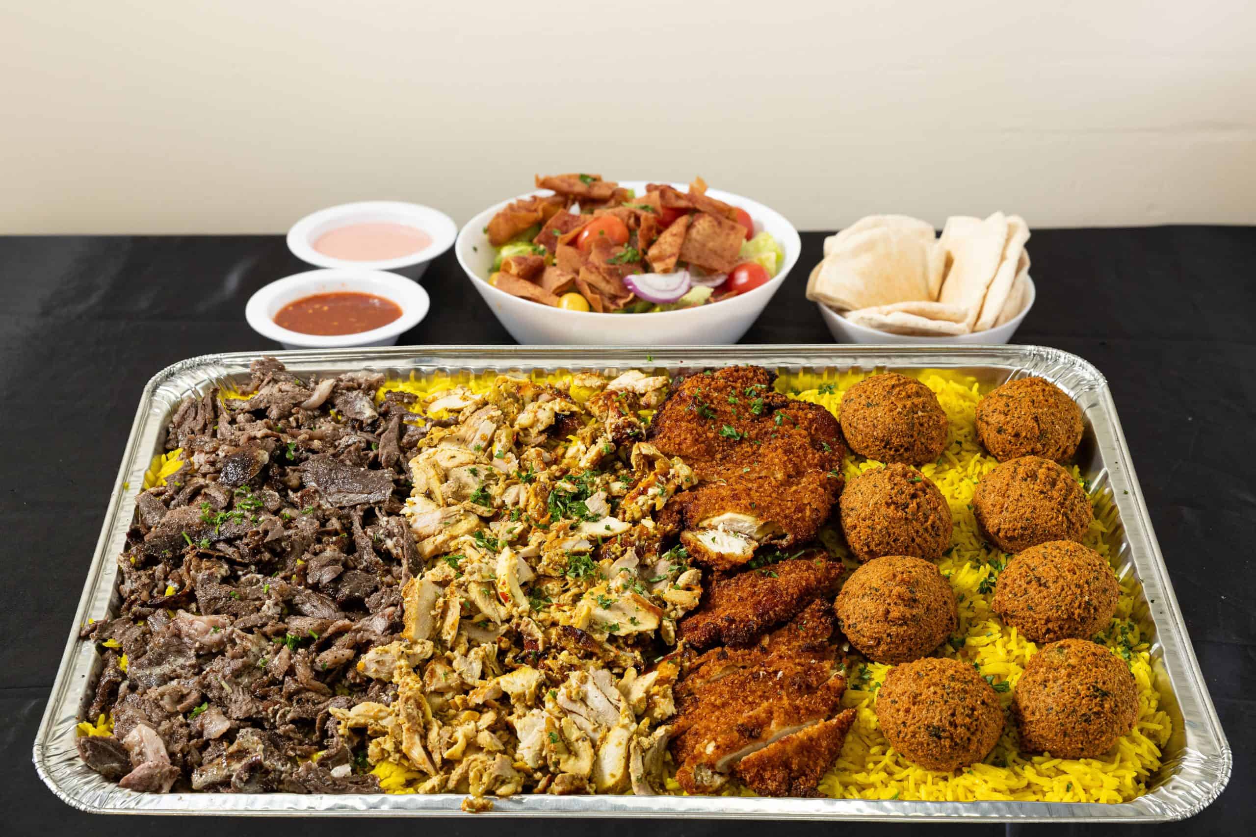 Family Tray at Shawarma House SD — Iraqi-Mediterranean catering combo of slow-roasted beef shawarma, hand-shaved chicken shawarma, falafel, basmati rice, two salads, and hummus, feeds 4 to 7 — Ocean Beach, San Diego